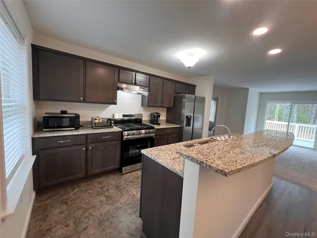 a kitchen with stainless steel appliances granite countertop a sink stove and refrigerator