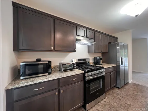 a kitchen with stainless steel appliances granite countertop a stove a microwave and a refrigerator