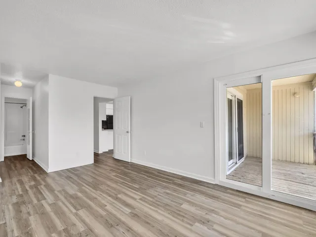 a view of an empty room with wooden floor and door