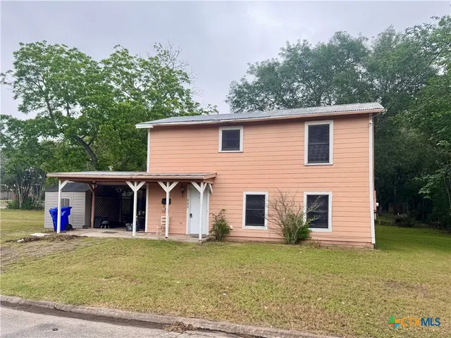 a view of a house with backyard and trees
