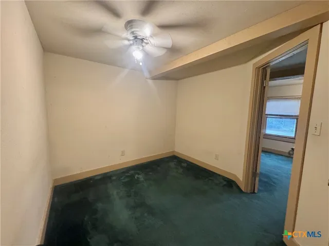 an empty room with a ceiling fan and a window