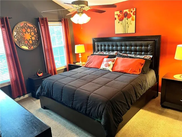 a bedroom with a bed and a mirror on dresser next to a window