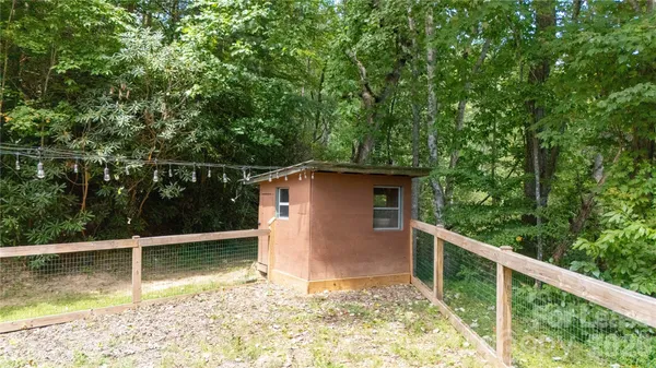 a view of backyard with large trees and wooden fence