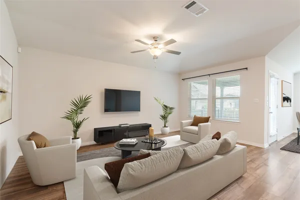 a living room with furniture kitchen view and a wooden floor