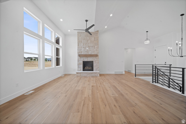 1117 East Shilow Road, Unit 106 Erda, UT 84074 - Photo 2 of 21 Spacious living area featuring high vaulted ceilings, expansive multi-pane windows, a stone-clad fireplace with a wood mantel, wood-finish flooring, and a modern black metal railing