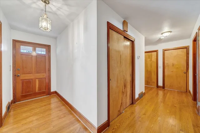 a view of a hallway with wooden floor and a bathroom