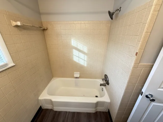 a view of an empty room with wooden floor fireplace and a window