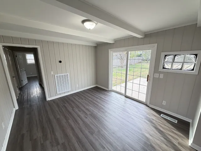 an empty room with wooden floor fan and windows