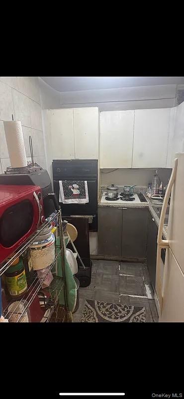 1020 Grand Concourse, Unit 5X Bronx, NY 10451 - Photo 7 of 10 Kitchen with black oven, freestanding refrigerator, white cabinets, and light countertops