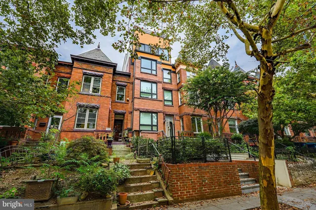a view of a kitchen with kitchen island stainless steel appliances wooden floor and a large window