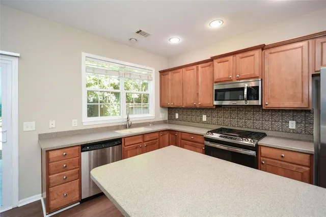 a kitchen with stainless steel appliances a stove sink microwave and cabinets