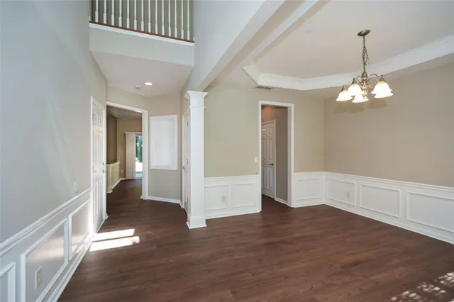 a view of a hallway with wooden floor and chandelier
