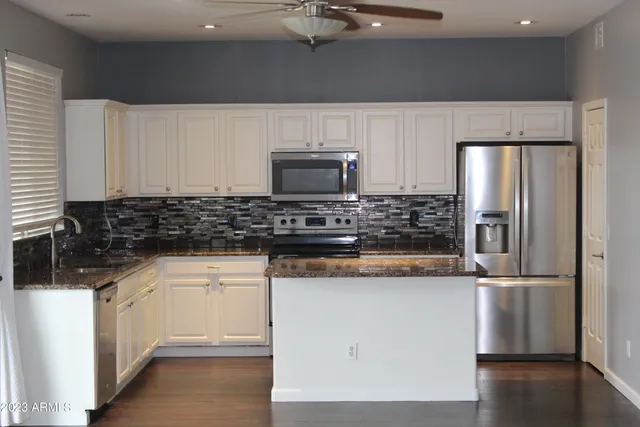 a kitchen with stainless steel appliances granite countertop a sink and a refrigerator