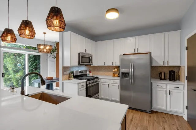 a kitchen with stainless steel appliances granite countertop a sink a stove and a refrigerator