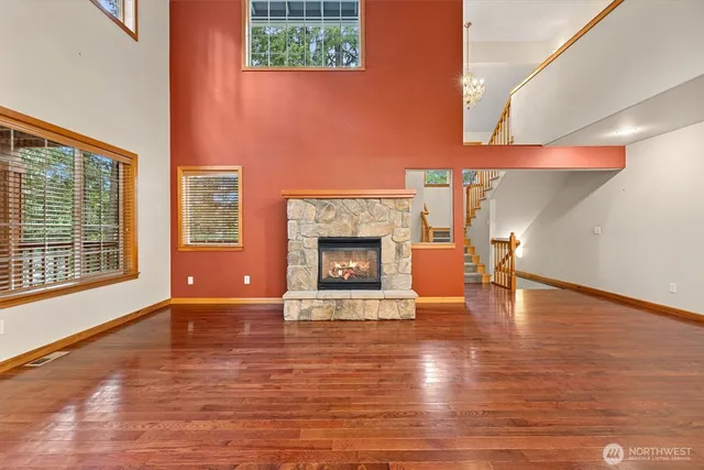 a view of an empty room with kitchen view and wooden floor