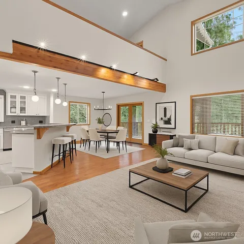 a living room with stainless steel appliances kitchen island granite countertop a refrigerator a stove top oven and a dining table with wooden floor