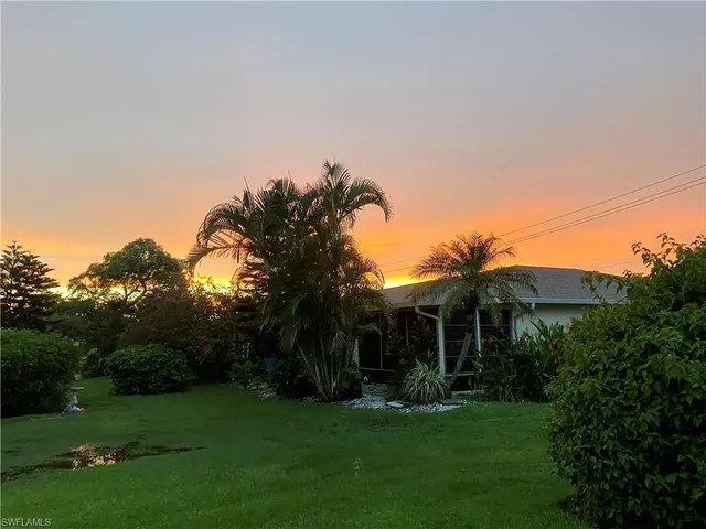 a front view of a house with a garden and trees