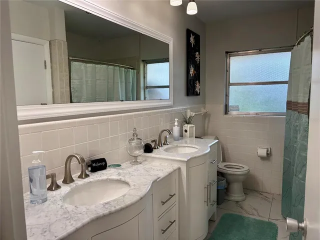 a bathroom with a granite countertop sink a toilet and mirror