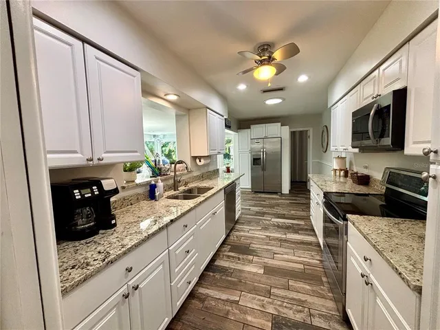 a large kitchen with kitchen island granite countertop a counter space a sink and stainless steel appliances