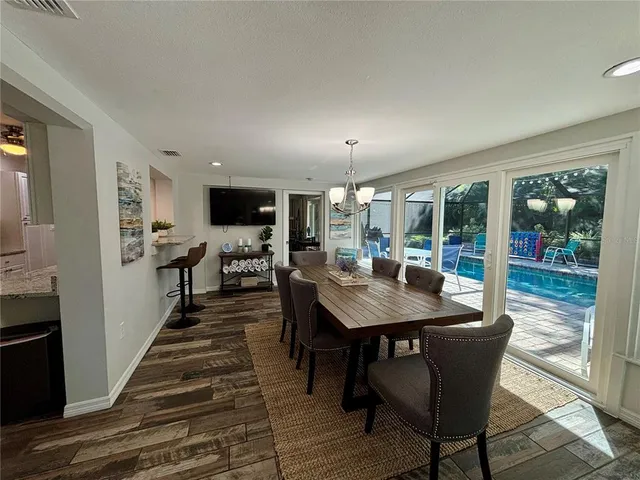 a dining hall with stainless steel appliances kitchen island granite countertop a table chairs and a refrigerator