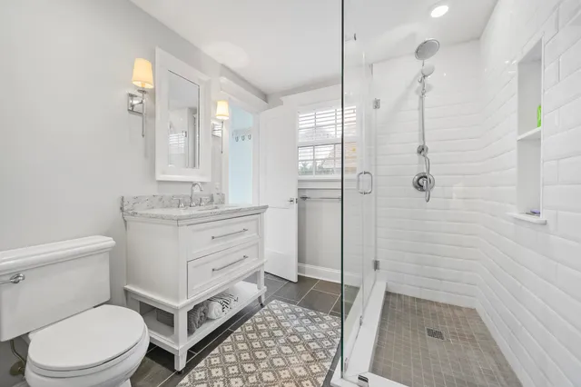 a bathroom with a sink a toilet a mirror and shower