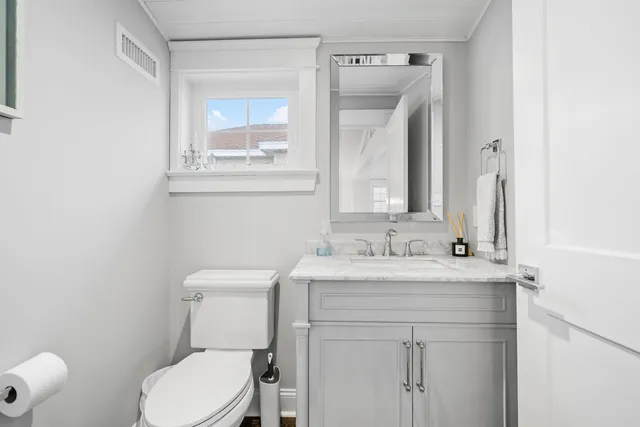 a bathroom with a granite countertop toilet sink and mirror