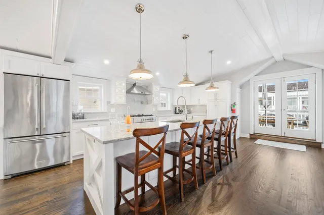 a kitchen with stainless steel appliances a dining table chairs sink and cabinets
