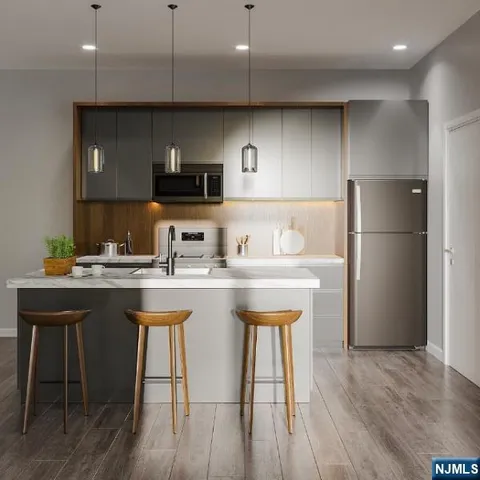 a kitchen with stainless steel appliances granite countertop a refrigerator a sink a stove a microwave and wooden floor