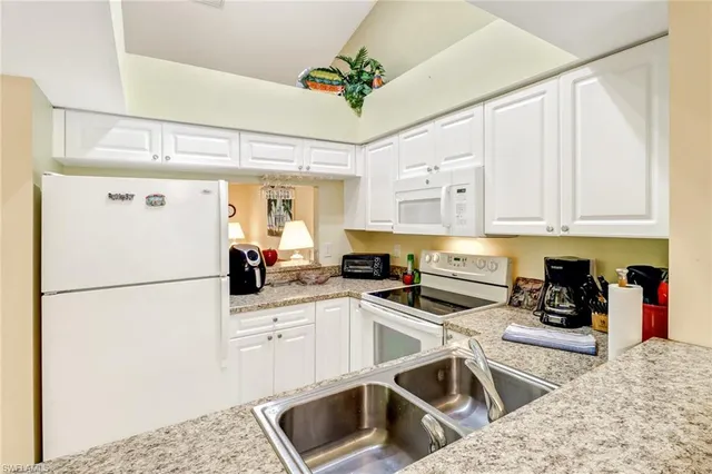 a kitchen with stainless steel appliances granite countertop a refrigerator sink and white cabinets