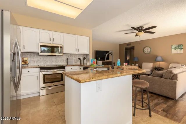 a living room with stainless steel appliances kitchen island granite countertop a stove and a sink