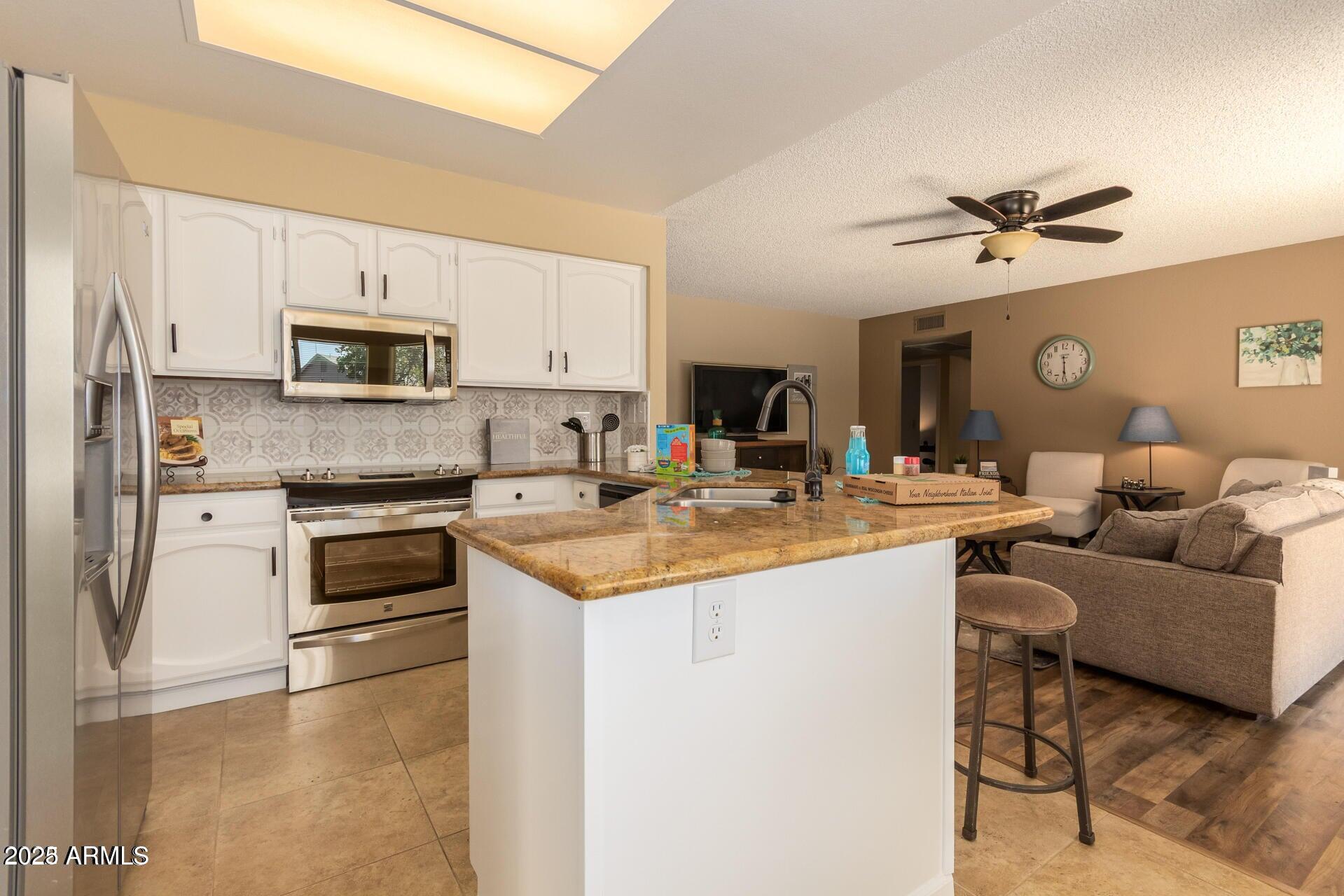 2221 West Rockwell Drive Chandler, AZ 85224 - Photo 7 of 14 a living room with stainless steel appliances kitchen island granite countertop a stove and a sink