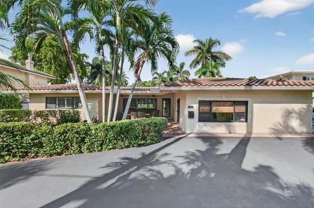 a front view of a house with a yard and potted plants