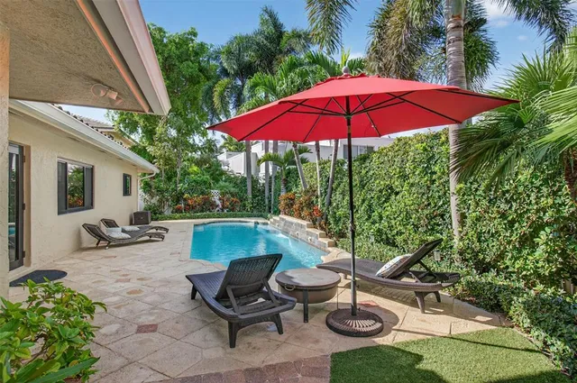 a backyard of a house with table and chairs under an umbrella