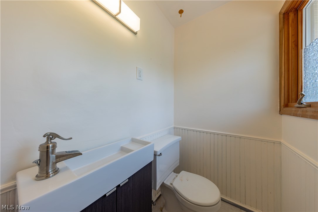 7969 Dines Road Novelty, OH 44072 - Photo 22 of 48 En-suite bathroom featuring a modern vanity with integrated sink, brushed nickel faucet, wall-mounted light fixture, beadboard paneling, and a wood-framed window with textured glass