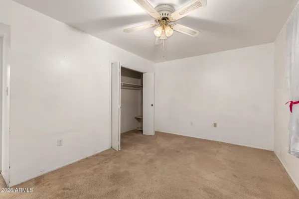 an empty room with a chandelier fan and windows