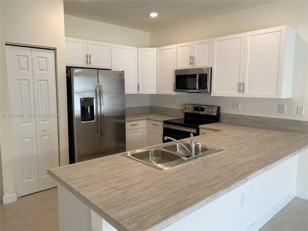 a kitchen with stainless steel appliances granite countertop a refrigerator sink and stove