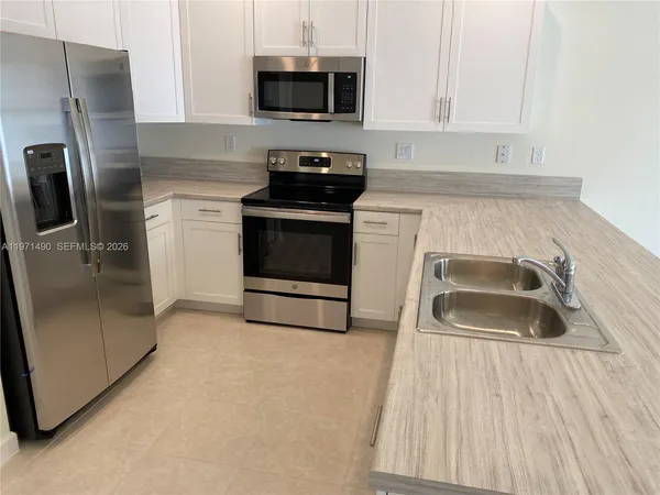 a kitchen with granite countertop a sink stove and refrigerator