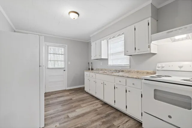 a kitchen with granite countertop white cabinets and white appliances