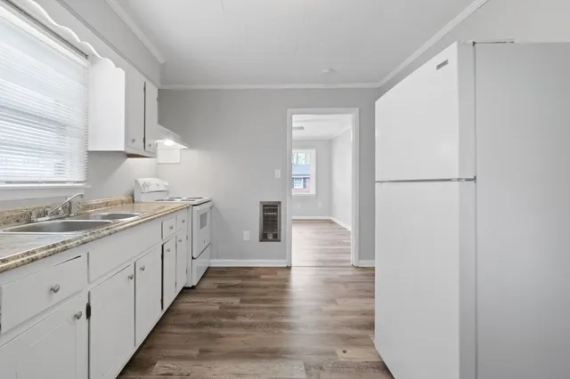 a kitchen with sink a refrigerator and white cabinets