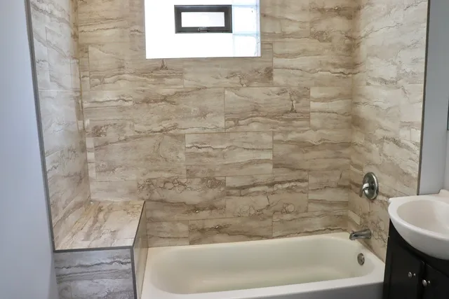 a bathroom with a tub a sink and mirror