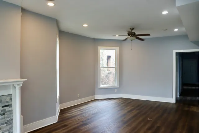 a view of an empty room with a window and wooden floor