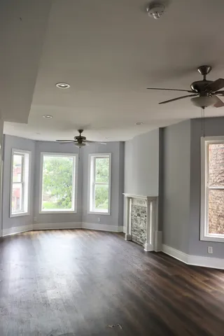 a view of an empty room with a window and wooden floor