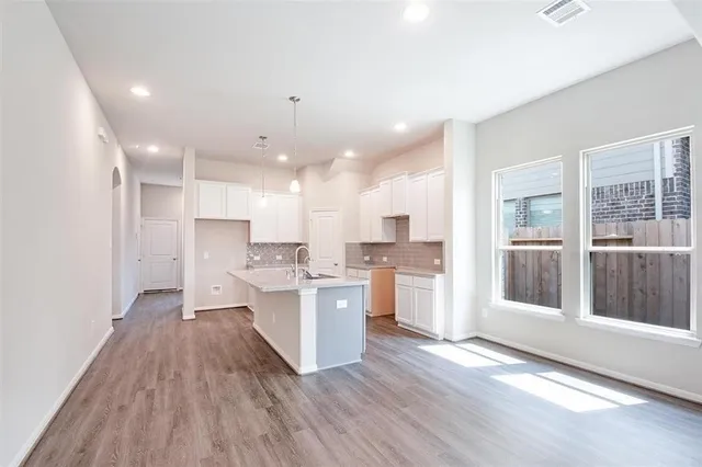 a view of a kitchen with center island wooden floor and stainless steel appliances