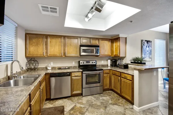 a kitchen with stainless steel appliances granite countertop sink stove top oven and cabinets