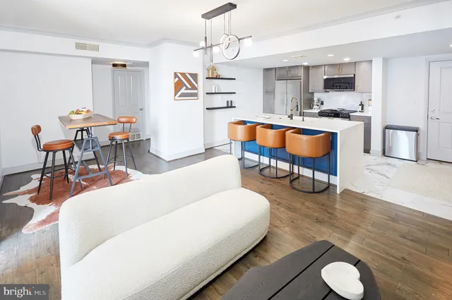 a living room with stainless steel appliances furniture and a kitchen view