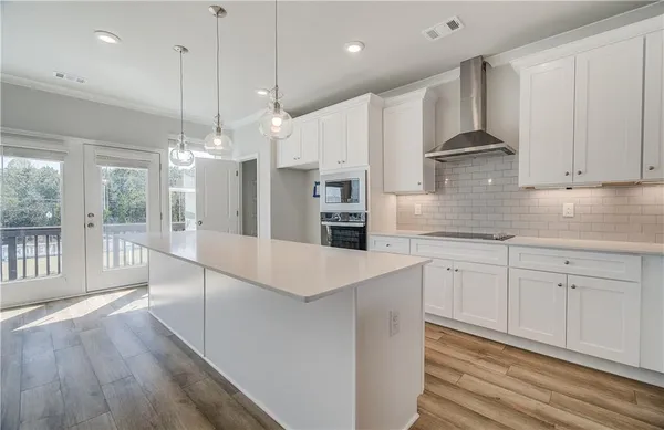 a large kitchen with granite countertop a large white kitchen island a sink stainless steel appliances and cabinets
