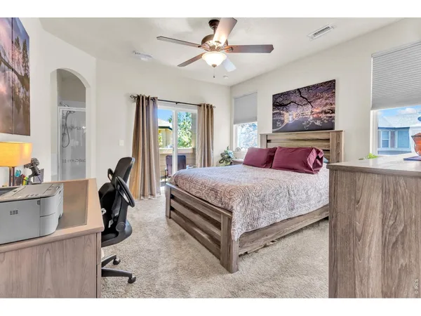 a bedroom with a bed a computer on the desk and a large mirror