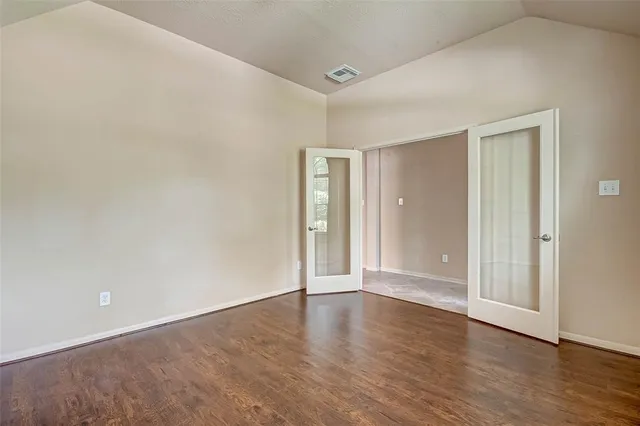a view of an empty room with wooden floor and closet