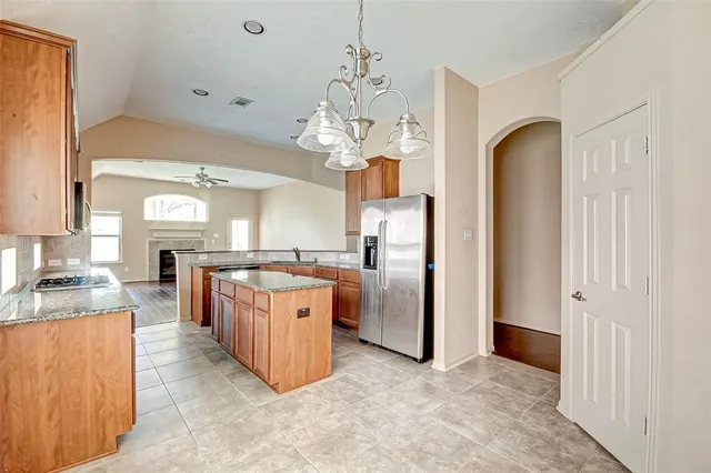 a large kitchen with stainless steel appliances granite countertop a refrigerator a sink dishwasher a stove and a dining table with wooden floor