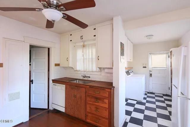 a room with a black white checkered floor and white cabinets